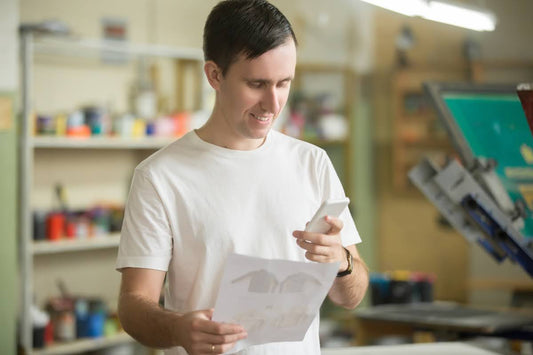 A man working in a t-shirt printing shop, learning how to use DTF transfer.